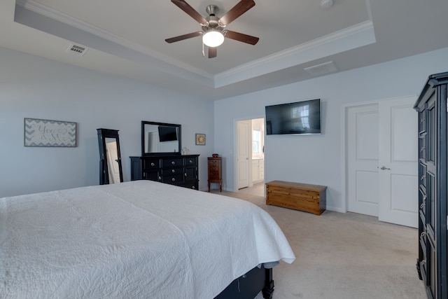 bedroom with light carpet, connected bathroom, a tray ceiling, and ceiling fan