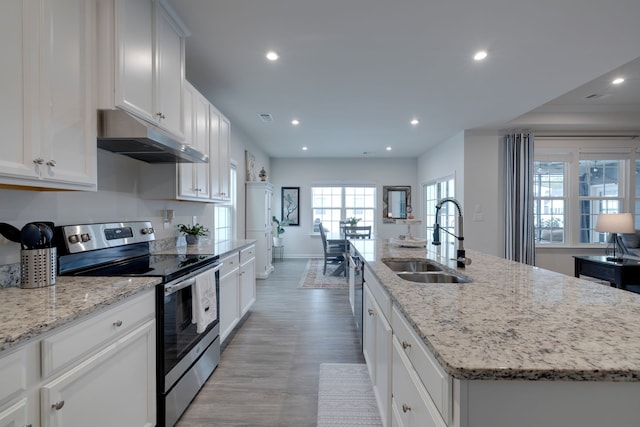 kitchen with a kitchen island with sink, sink, electric stove, white cabinetry, and light hardwood / wood-style flooring