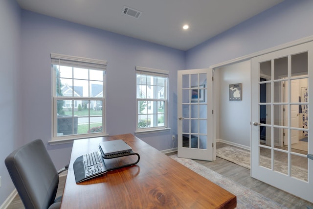 home office featuring light wood-type flooring, a wealth of natural light, and french doors