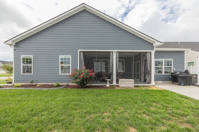 rear view of house featuring a sunroom, a patio area, and a yard