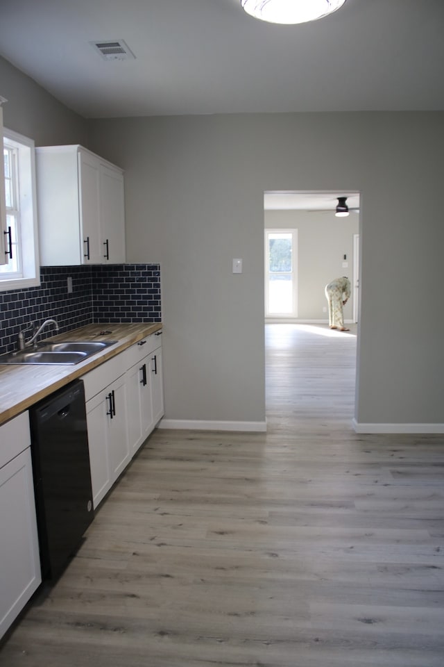 kitchen with black dishwasher, sink, white cabinetry, and wood counters