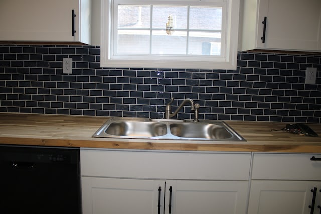 kitchen with black dishwasher, butcher block countertops, and tasteful backsplash