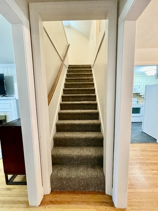 stairs with wood-type flooring and ornamental molding