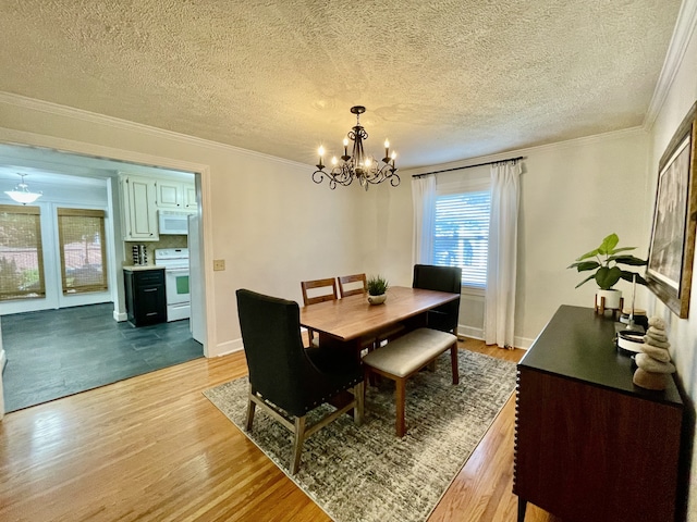 dining space with light hardwood / wood-style floors, a textured ceiling, crown molding, and a notable chandelier