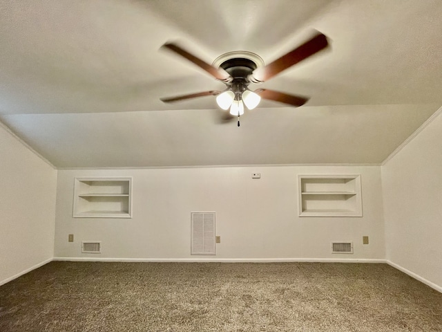 additional living space with lofted ceiling, ceiling fan, dark colored carpet, and built in shelves