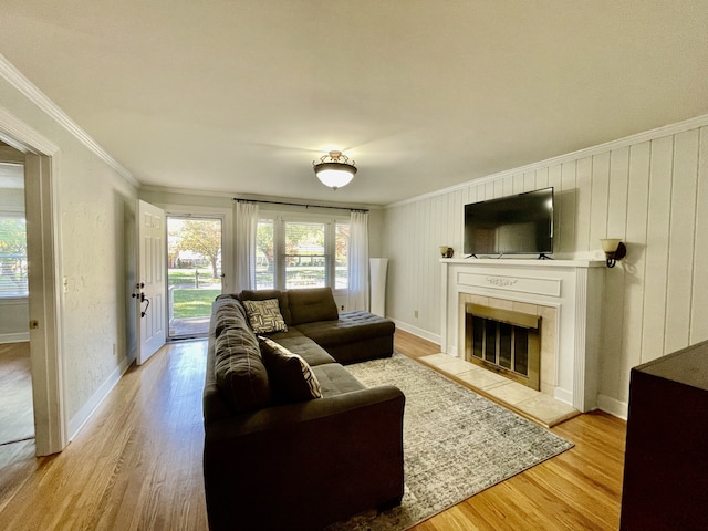 living room with a fireplace, light wood-type flooring, and crown molding