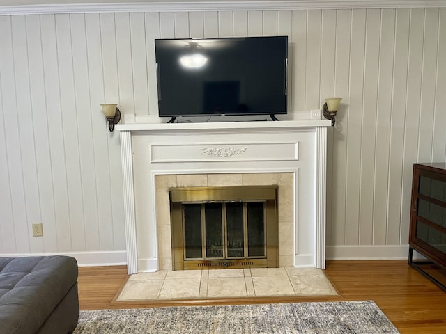 details with wood walls, hardwood / wood-style flooring, and a tile fireplace