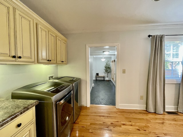 washroom with light wood-type flooring, cabinets, washing machine and dryer, and ornamental molding