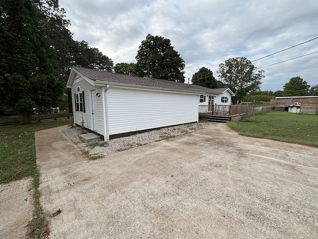 view of side of property featuring a lawn and a wooden deck