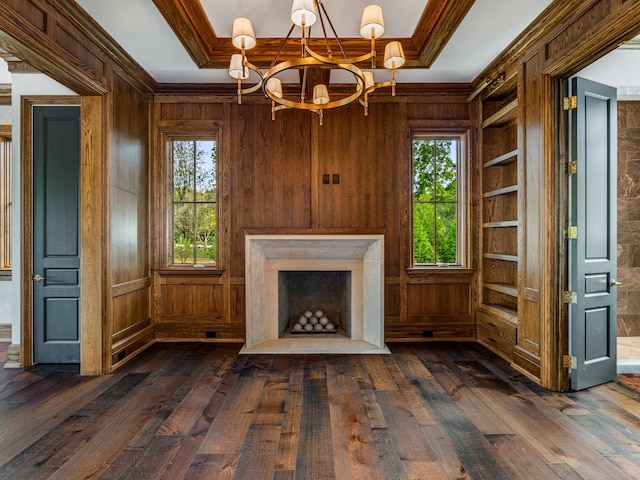 unfurnished living room featuring wooden walls, dark hardwood / wood-style flooring, built in features, and a wealth of natural light