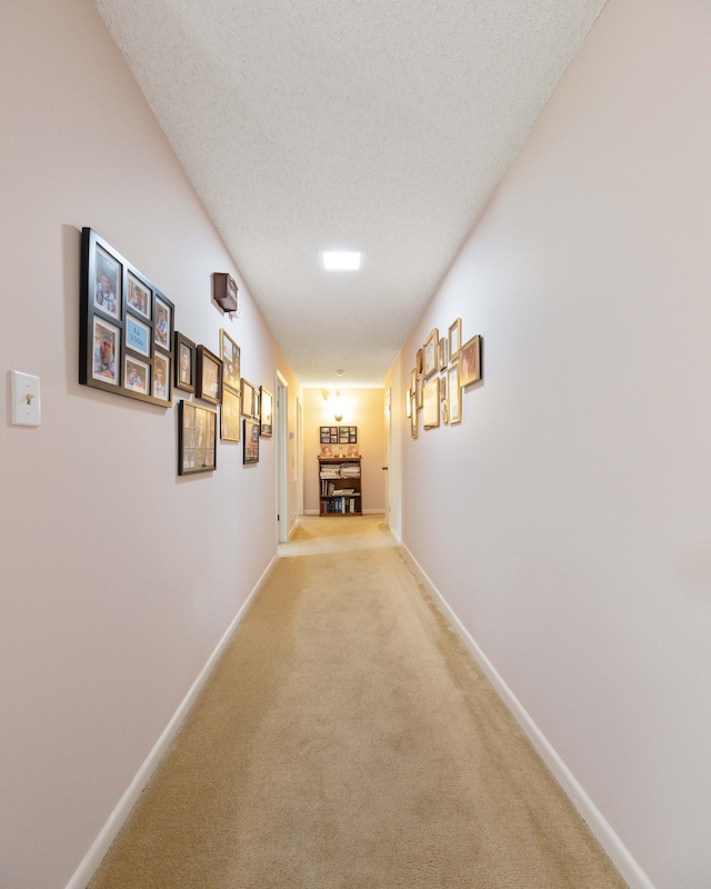 corridor featuring a textured ceiling and light colored carpet