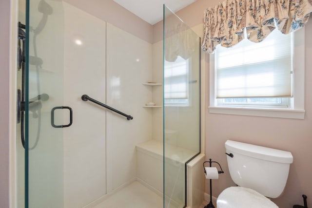 bathroom featuring a shower with shower door and toilet