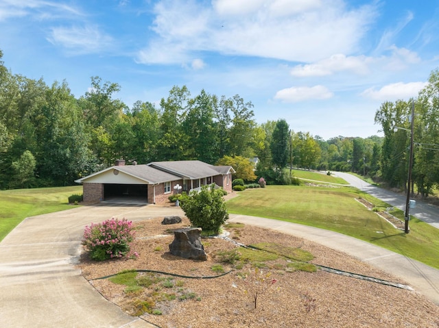 view of front of house featuring a chimney, curved driveway, a carport, a front yard, and brick siding