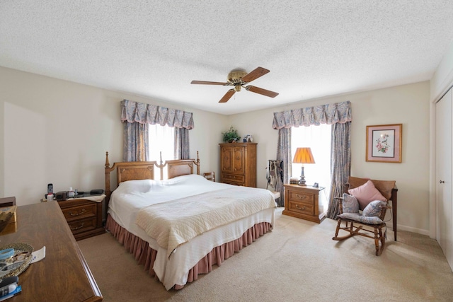 carpeted bedroom with multiple windows, a textured ceiling, ceiling fan, and a closet