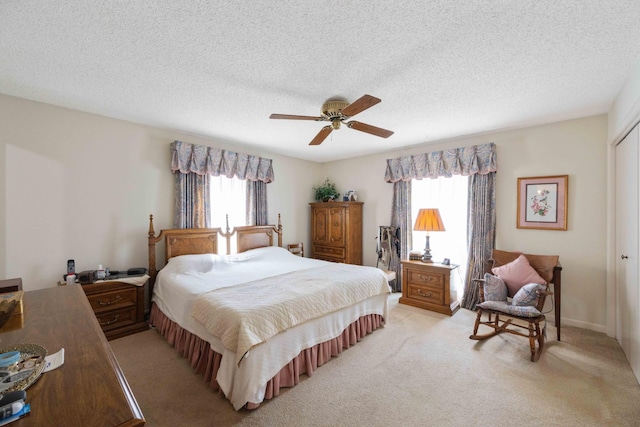 bedroom with a closet, a textured ceiling, light carpet, and ceiling fan