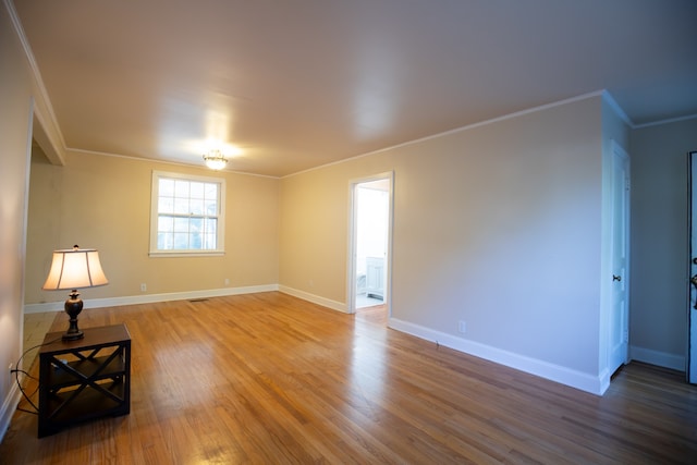 empty room featuring crown molding and wood-type flooring