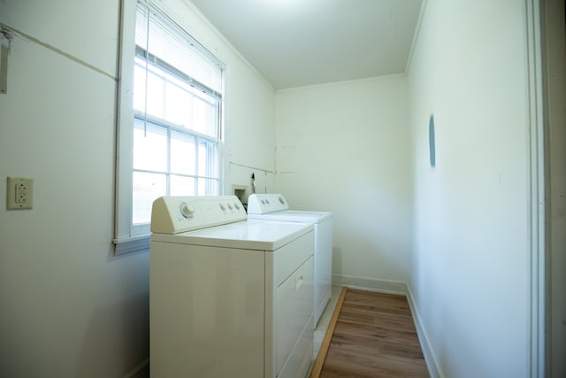 laundry room featuring washing machine and dryer, light hardwood / wood-style floors, and ornamental molding