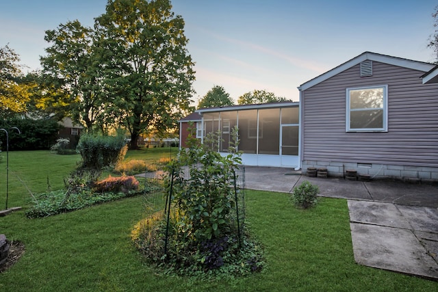 yard at dusk with a patio and a sunroom