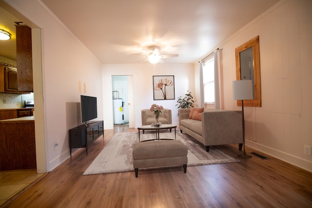 living room with electric water heater, crown molding, ceiling fan, and wood-type flooring