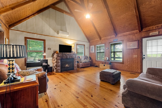 living room featuring beamed ceiling, light wood-type flooring, a fireplace, and a wealth of natural light