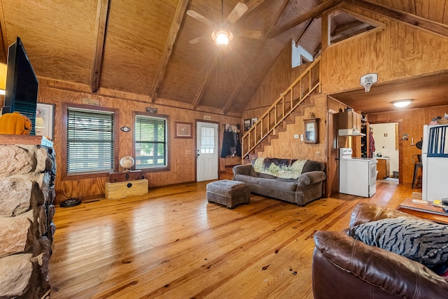 living room with lofted ceiling with beams, light wood-type flooring, wood walls, and wooden ceiling