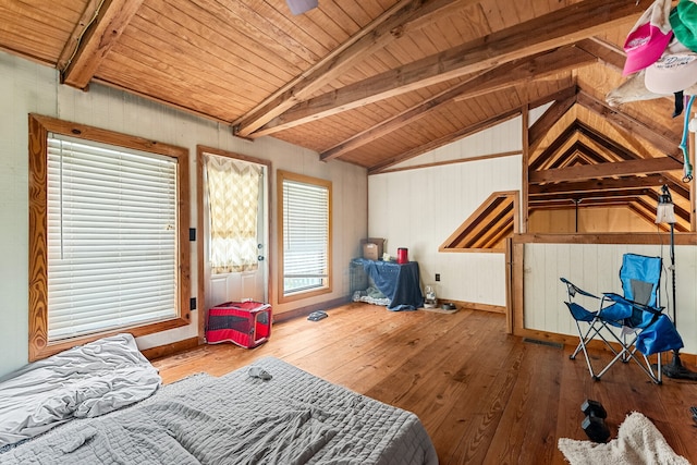 bedroom with lofted ceiling with beams, multiple windows, and hardwood / wood-style flooring