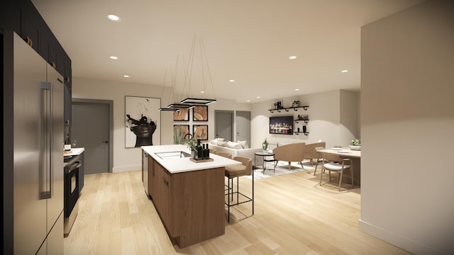 kitchen with a breakfast bar area, appliances with stainless steel finishes, a kitchen island, light hardwood / wood-style floors, and sink