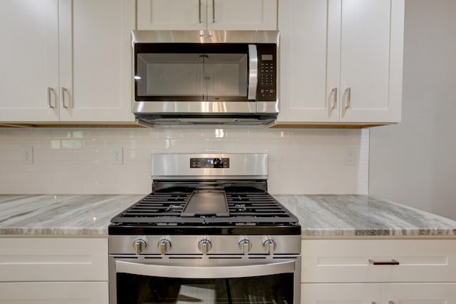 kitchen with backsplash, light stone counters, stainless steel appliances, and white cabinets