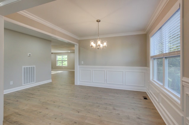 unfurnished dining area with an inviting chandelier, crown molding, and light hardwood / wood-style floors