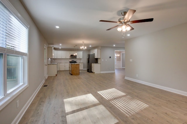 unfurnished living room featuring light hardwood / wood-style flooring, ceiling fan with notable chandelier, and sink