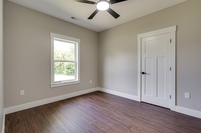 empty room featuring ceiling fan, visible vents, baseboards, and dark wood-type flooring