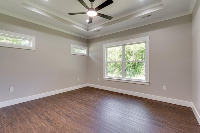 unfurnished room with a raised ceiling, crown molding, ceiling fan, and dark wood-type flooring