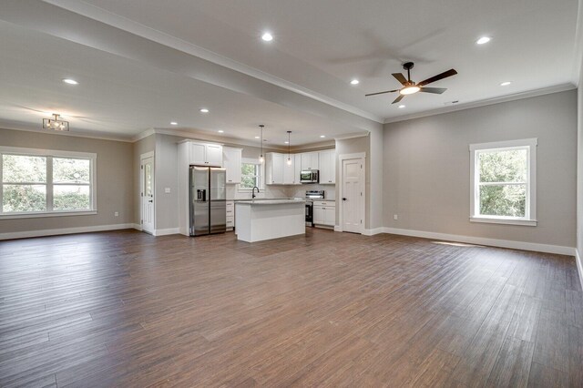 unfurnished living room with crown molding, baseboards, ceiling fan, and dark wood-style flooring