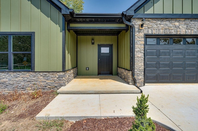 property entrance featuring board and batten siding, an attached garage, and stone siding