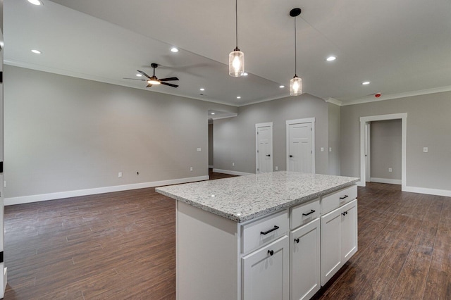 kitchen with hanging light fixtures, a center island, a ceiling fan, open floor plan, and ornamental molding