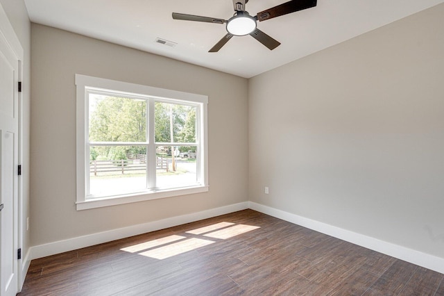 empty room with baseboards, ceiling fan, dark wood-style floors, and visible vents