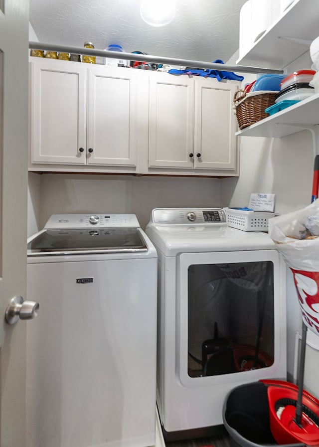 clothes washing area featuring washer and clothes dryer, cabinets, and a textured ceiling