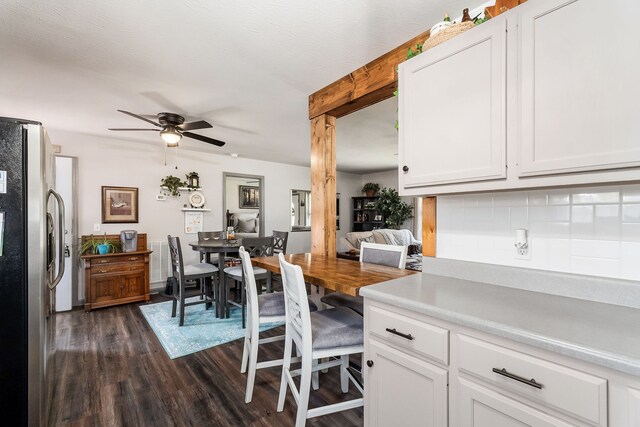 interior space with dark wood-type flooring, tasteful backsplash, white cabinets, stainless steel refrigerator, and ceiling fan