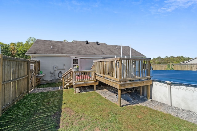 rear view of property featuring a wooden deck and a lawn