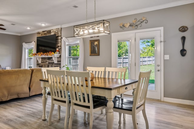 dining area featuring a fireplace, ornamental molding, and light wood-type flooring