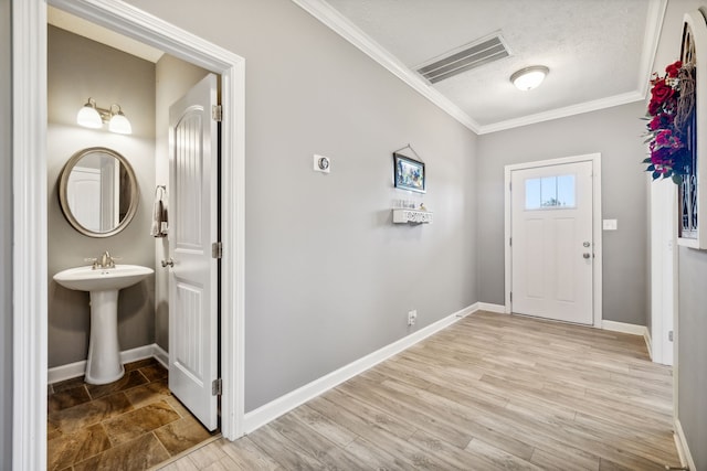 entryway featuring light hardwood / wood-style floors, crown molding, and a textured ceiling