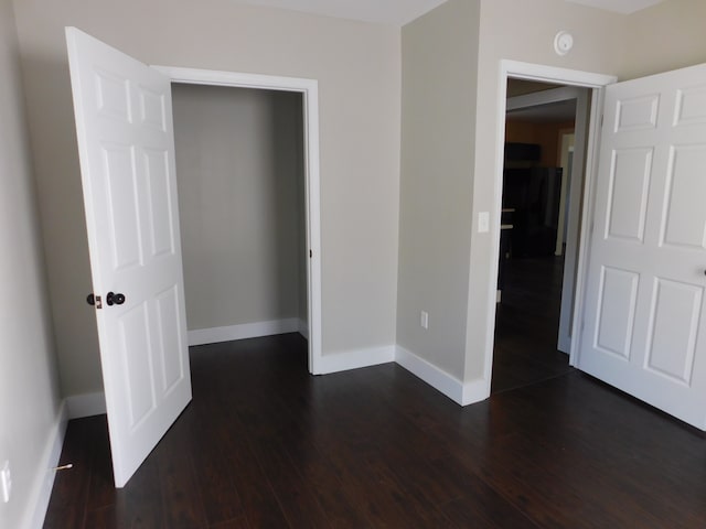 unfurnished bedroom featuring a closet and dark hardwood / wood-style flooring