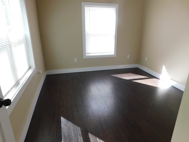 spare room with dark wood-type flooring and a wealth of natural light