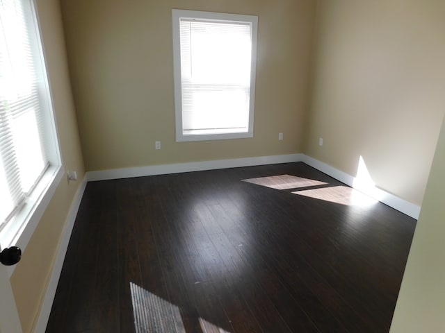 empty room with dark wood-type flooring and plenty of natural light