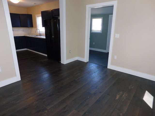 kitchen featuring backsplash, black fridge, dark hardwood / wood-style flooring, and sink