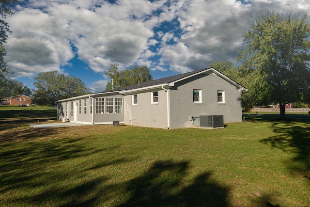 rear view of house featuring central AC unit, a patio area, and a lawn