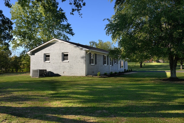 view of side of home featuring cooling unit and a yard