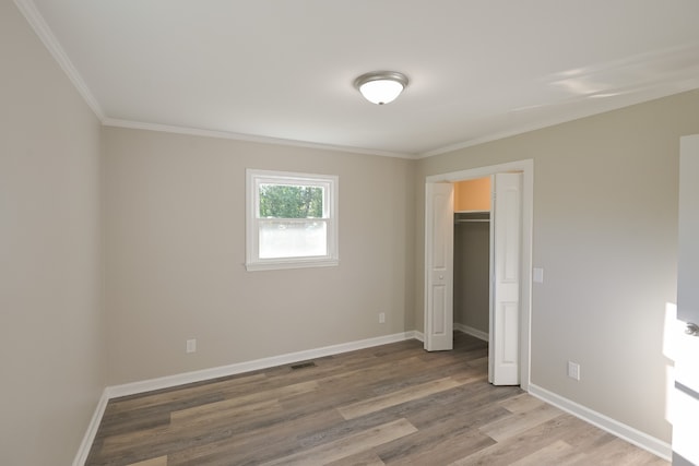 unfurnished bedroom featuring a closet, ornamental molding, and hardwood / wood-style flooring