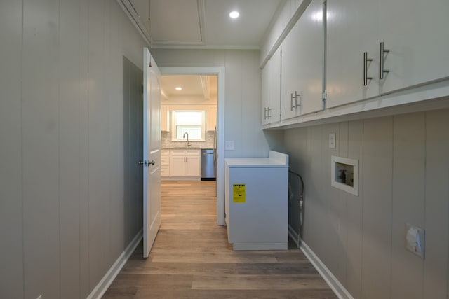 laundry room with sink, crown molding, light hardwood / wood-style flooring, washer hookup, and cabinets