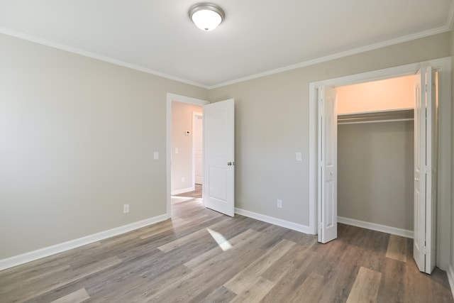 unfurnished bedroom featuring hardwood / wood-style floors, a closet, and ornamental molding